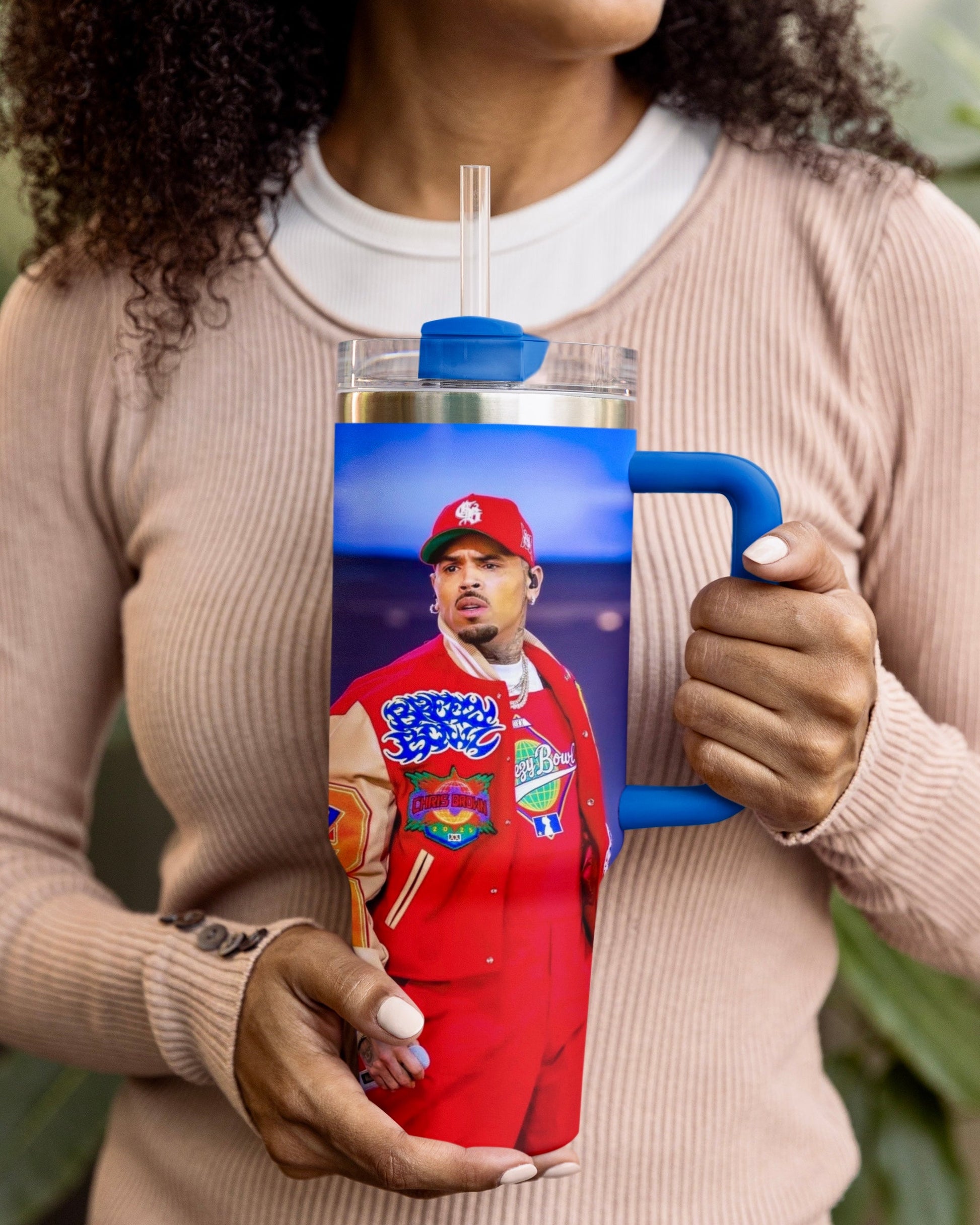 Person holding a Chris Brown tumbler with a printed design 