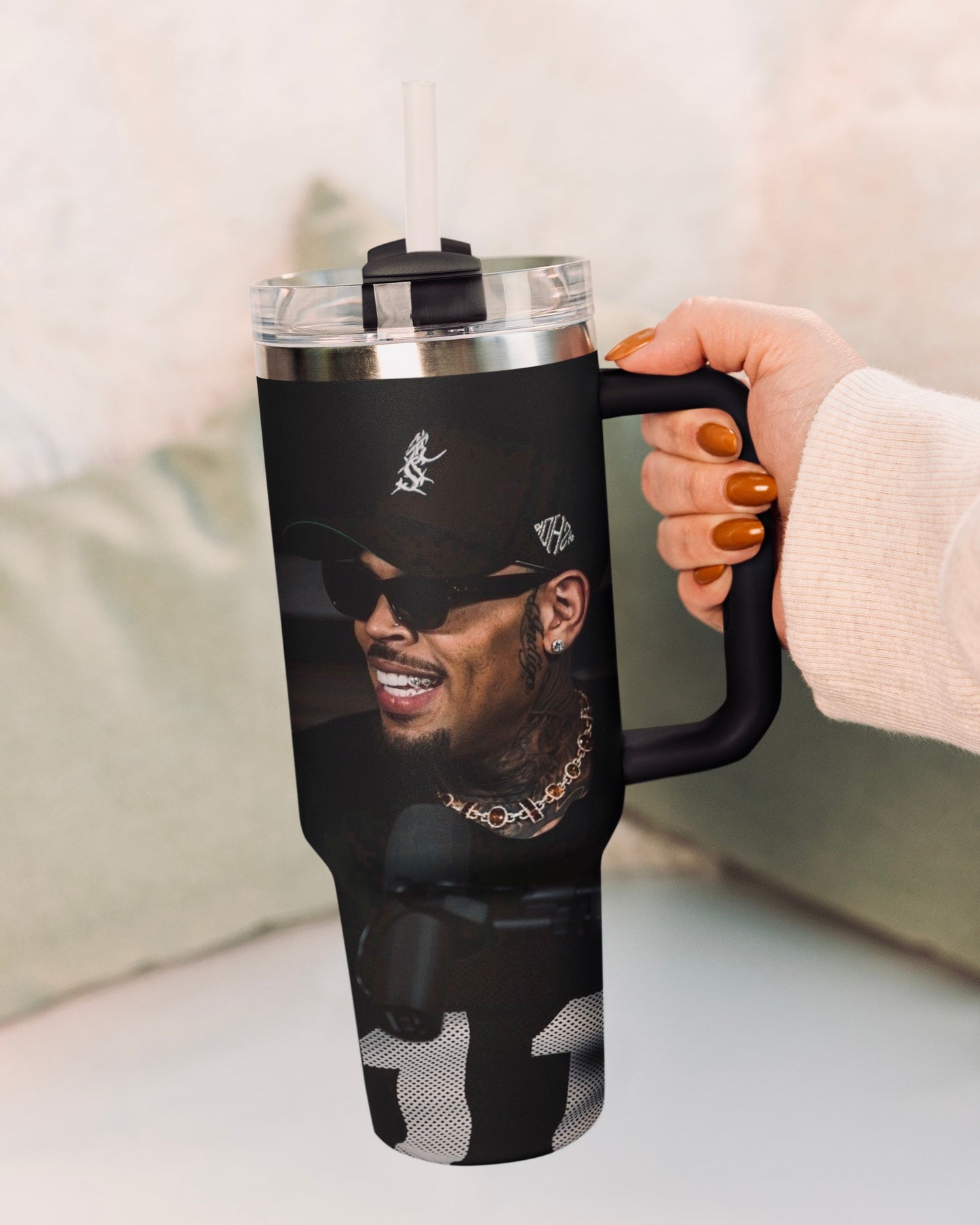 Person holding a black 30oz Chris Brown insulated tumbler with a graphic design on a light background
