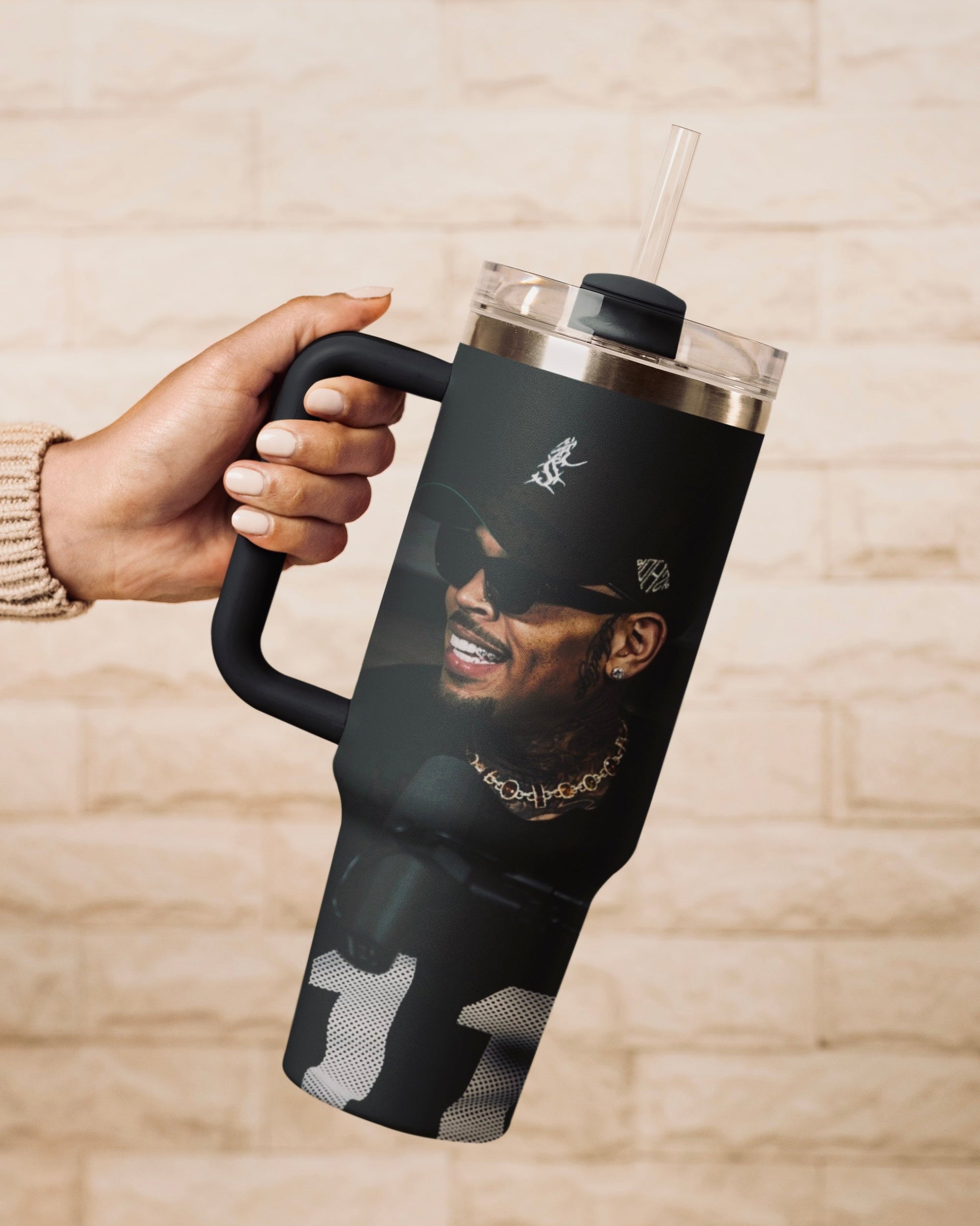Person holding a black 30oz Chris Brown insulated tumbler with straw 